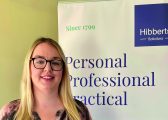 Michaela Warner standing in front of a Hibberts Solicitors Banner following her STEP qualification