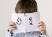 Image shows a young boy with dark hair and a blue shirt with his face covered by a piece of paper torn in half with a stick drawing of a woman and man on each half for the Family Justice Council Blog