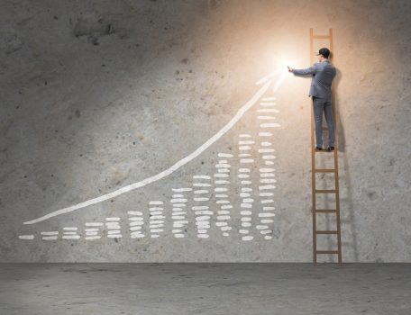 Image of graph showing an increase from left to right with a man in a suit on a ladder pointing to the top right side of the graph to represent The Economic Crime and Corporate Transparency Act 2023